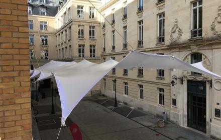Pose d'une structure couverte de tissus tendus dans une cour intérieure à Paris